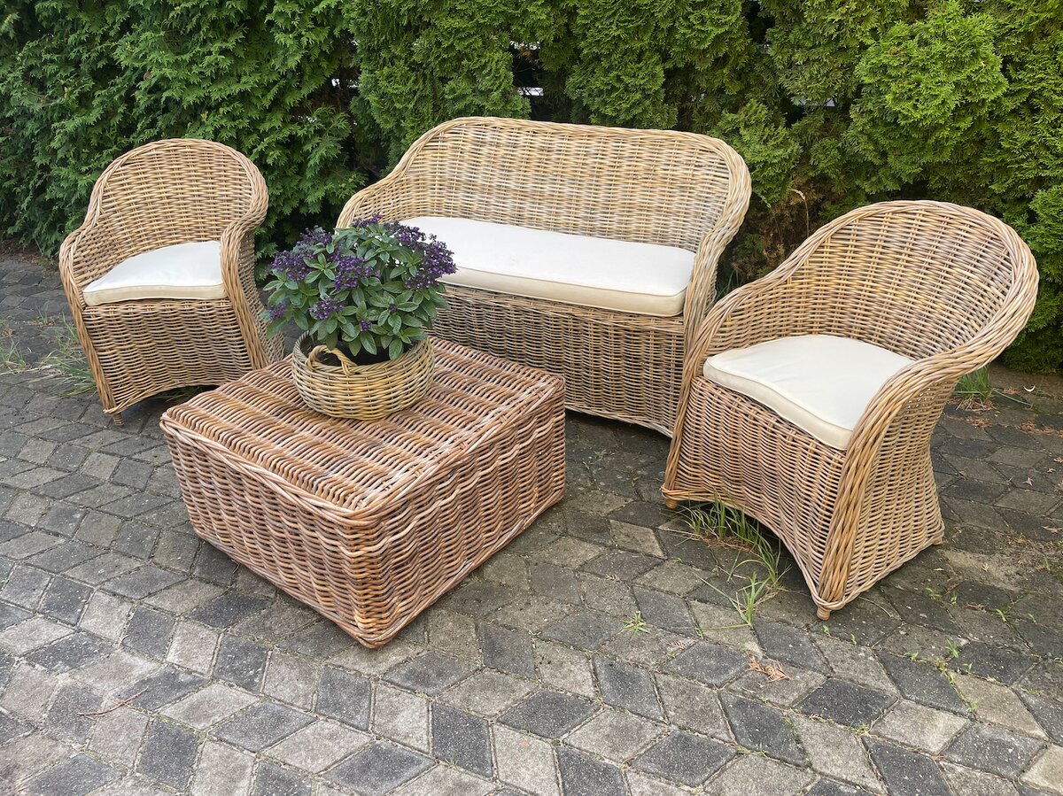 Komplet mebli rattanowych — sofa, dwa fotele i stolik kawowy na tarasie