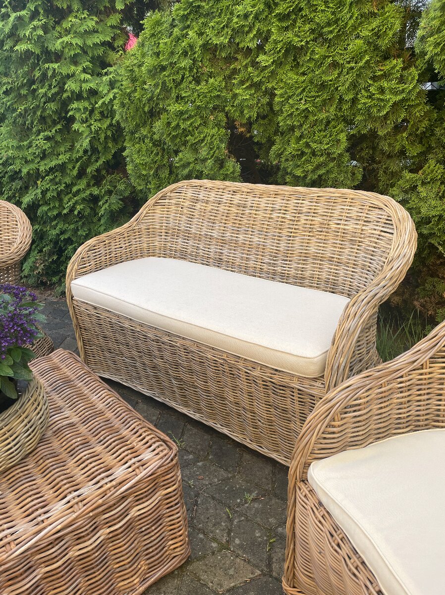 Sofa rattanowa dwuosobowa z kremową poduszką — ujęcie z boku